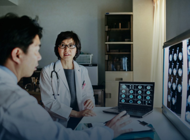 two doctors looking over mri images on a lenovo laptop