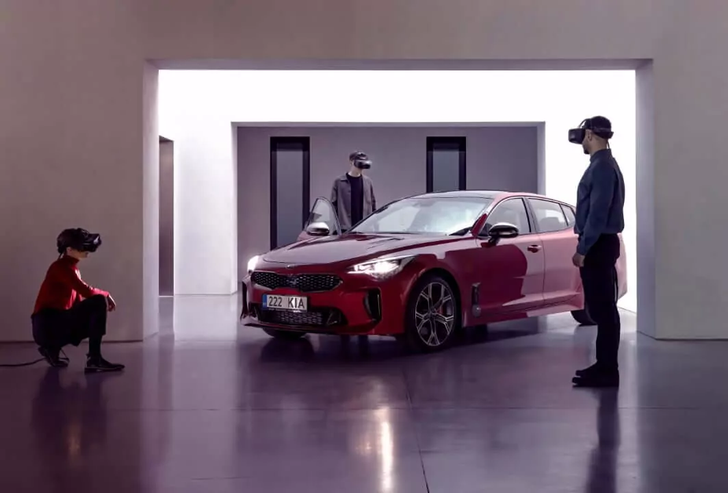 Three people in VR glasses near a car