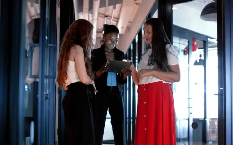 Three women are watching something on a tablet